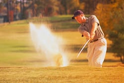Golfer Swinging in Sand Trap
